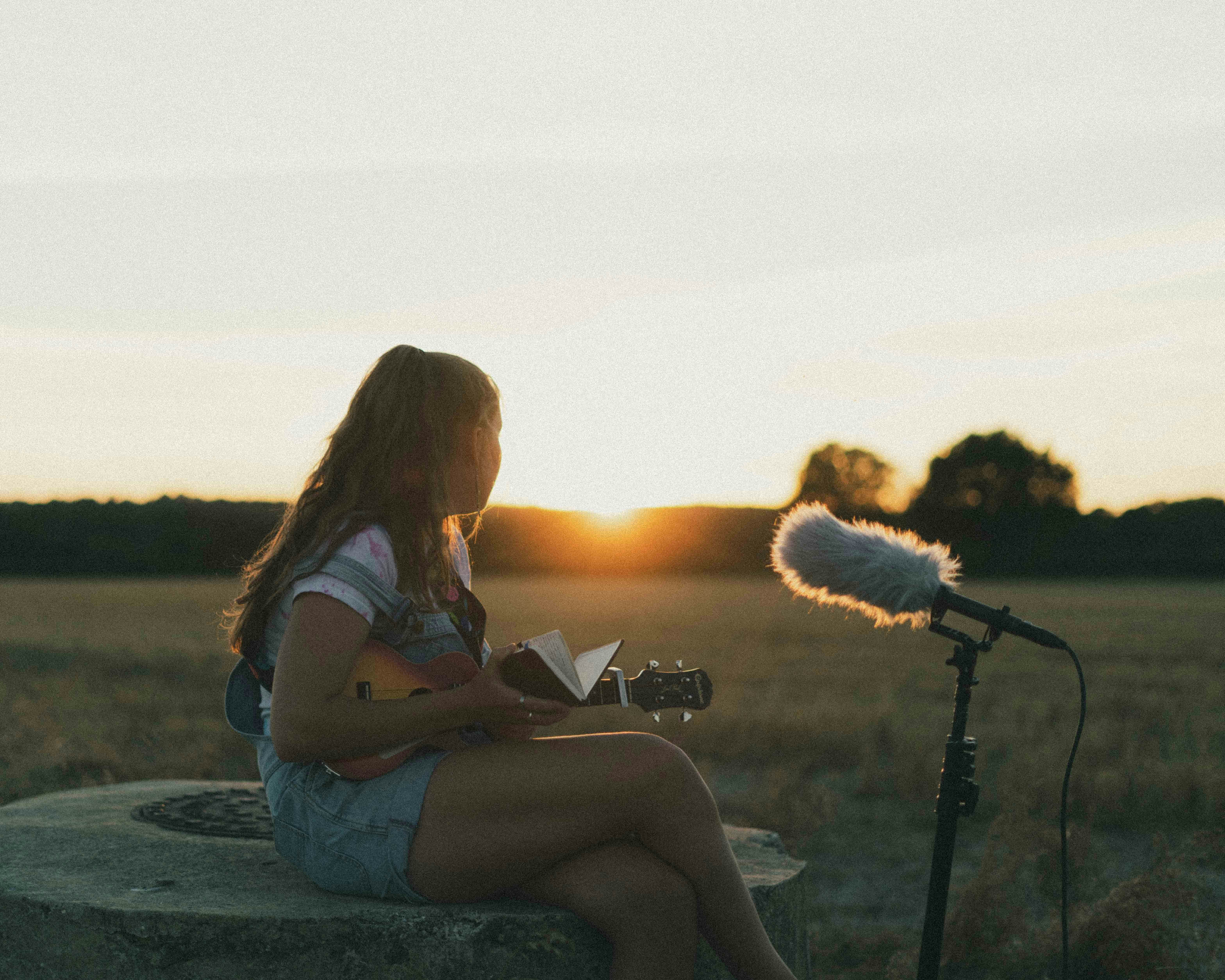 woman in white shirt sitting on gray concrete floor during sunset